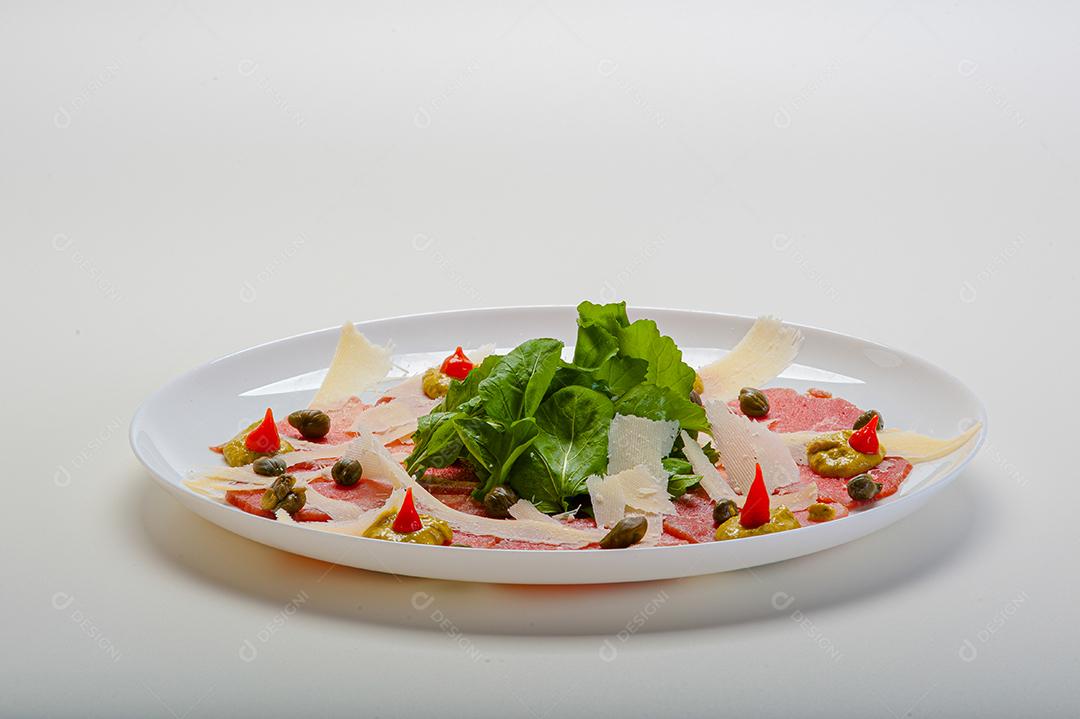 Carpaccio de salmão servido com rúcula e alcaparras.