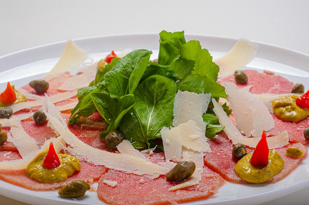 Carpaccio de salmão servido com rúcula e alcaparras.