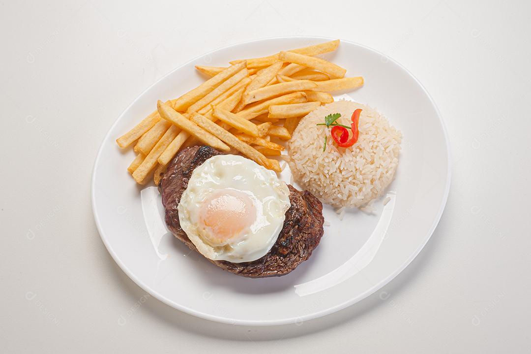 Prato de comida tipico brasileiro arroz batata frita ovo frito sobre prato branco
