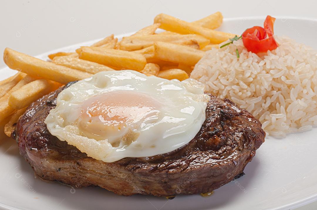 Prato de comida tipico brasileiro arroz batata frita ovo frito sobre prato branco