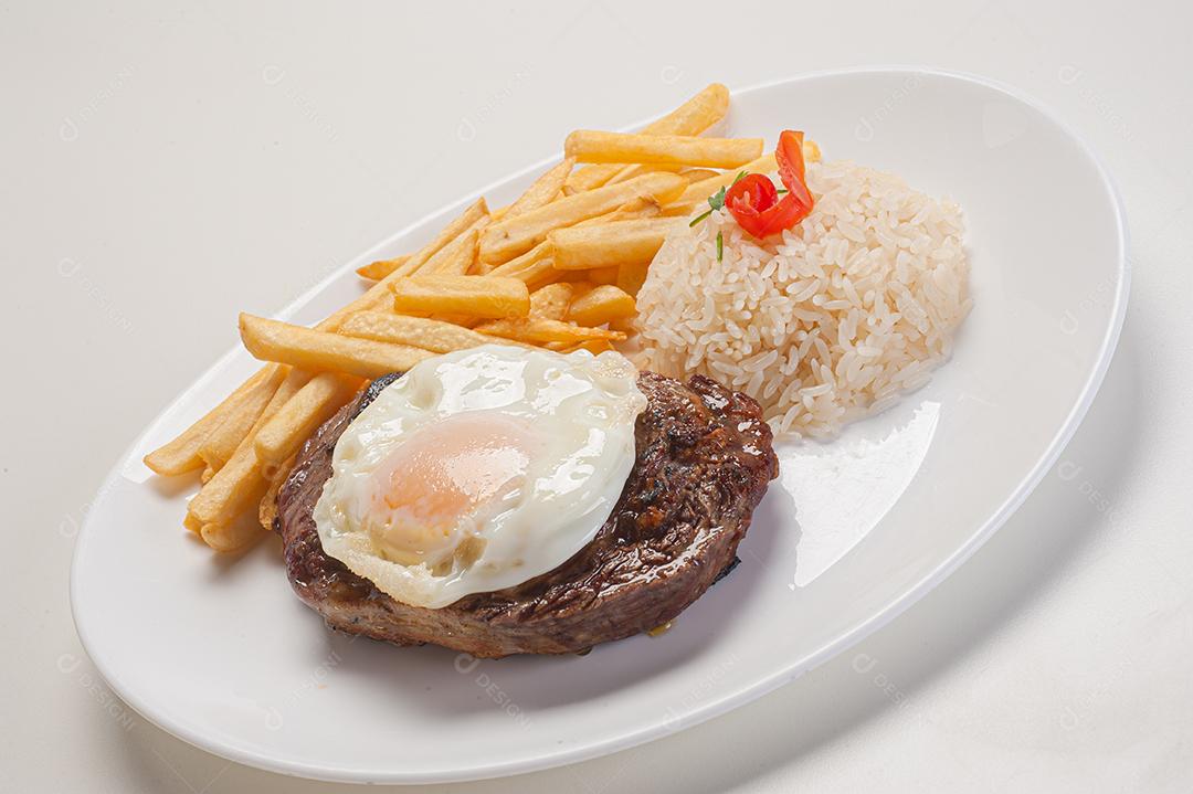 Prato de comida tipico brasileiro arroz batata frita ovo frito sobre prato branco