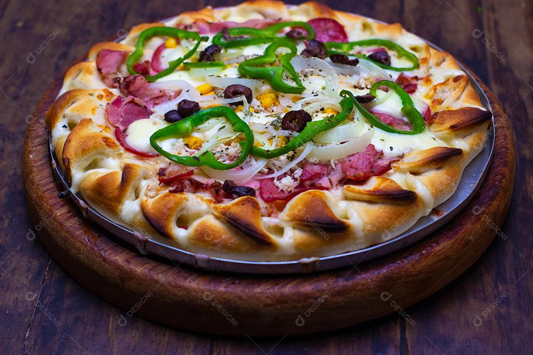Pizza super deliciosa de queijo com catupiry, calabresa, pimentão verde, cebola branca sobre mesa madeira