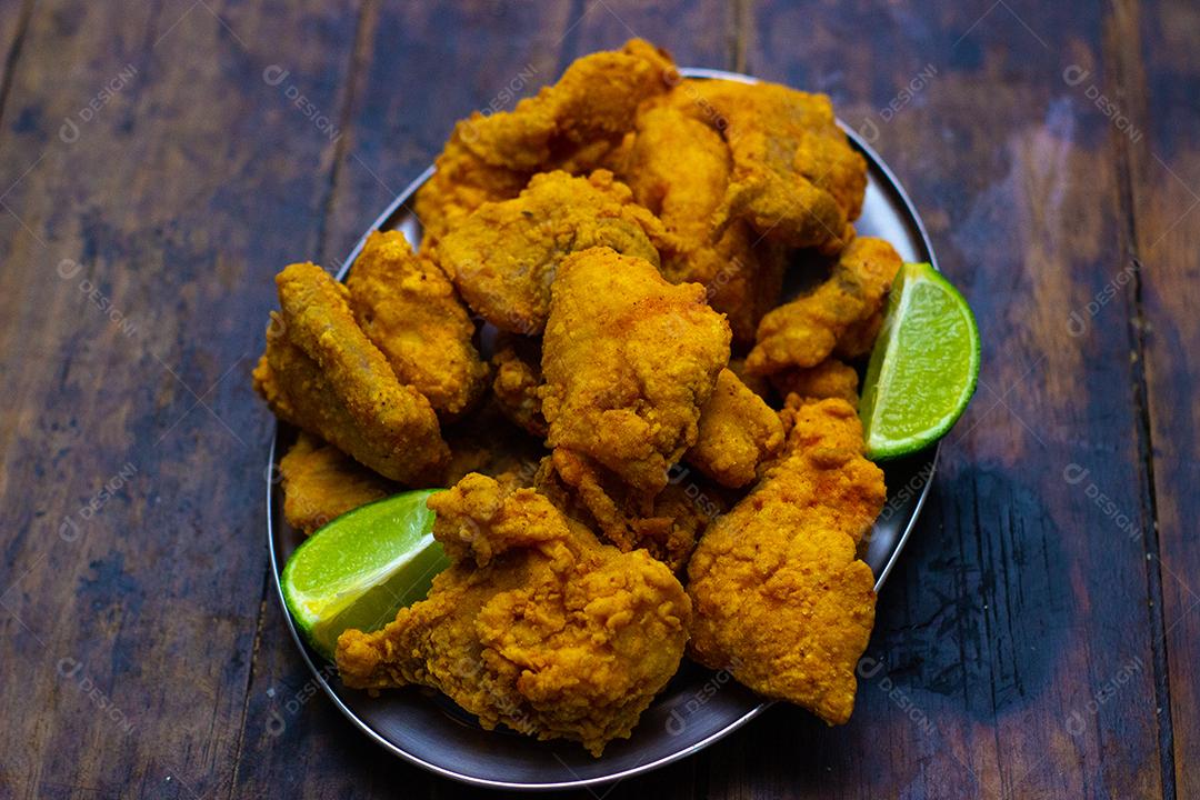 Frango frito com limão sobre mesa madeira.