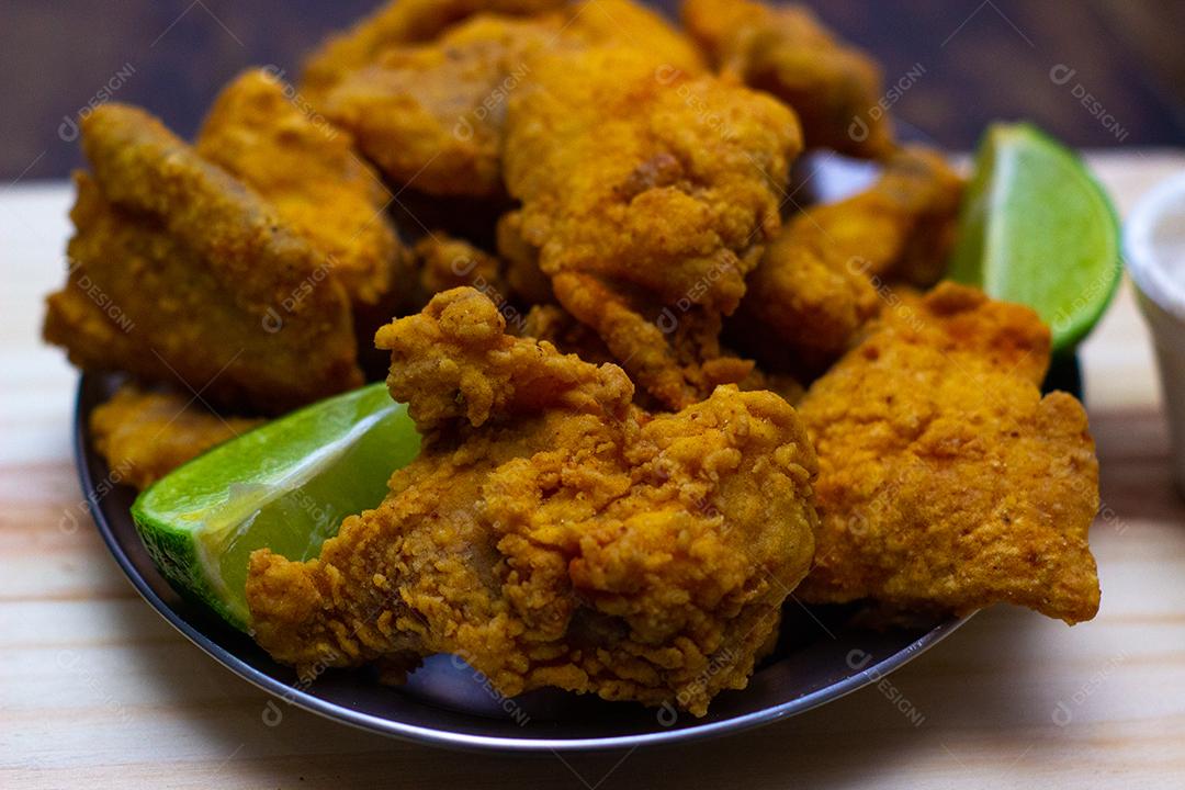 Frango frito com limão sobre mesa madeira.
