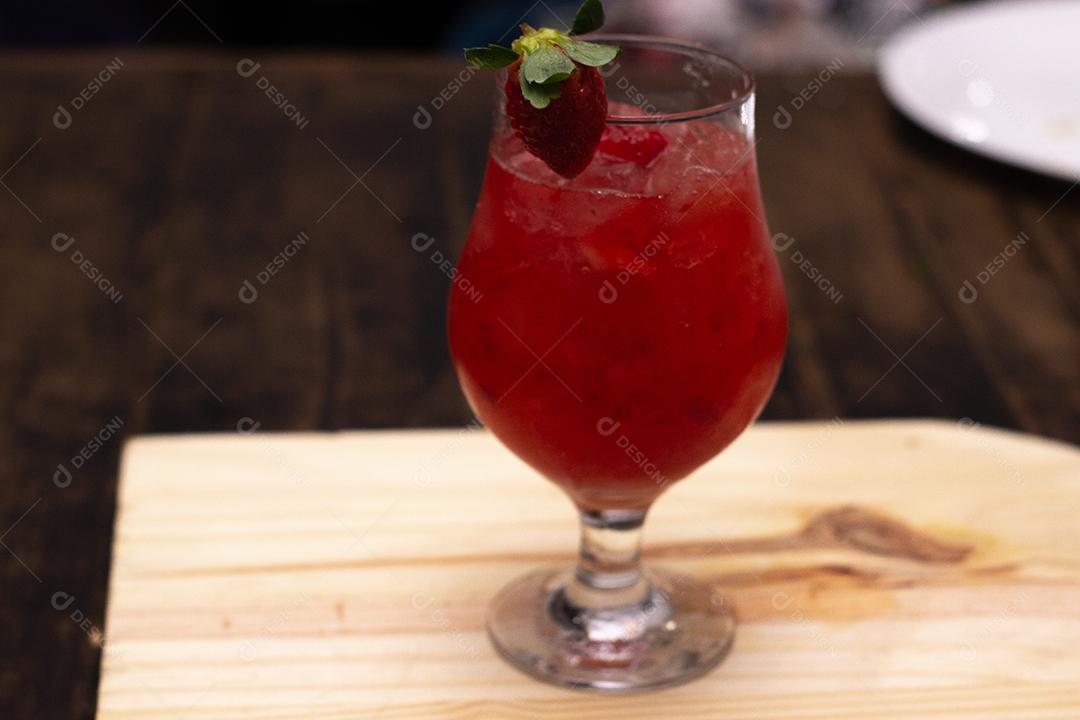 Cocktail de Morango sobre placa e mesa de madeira.