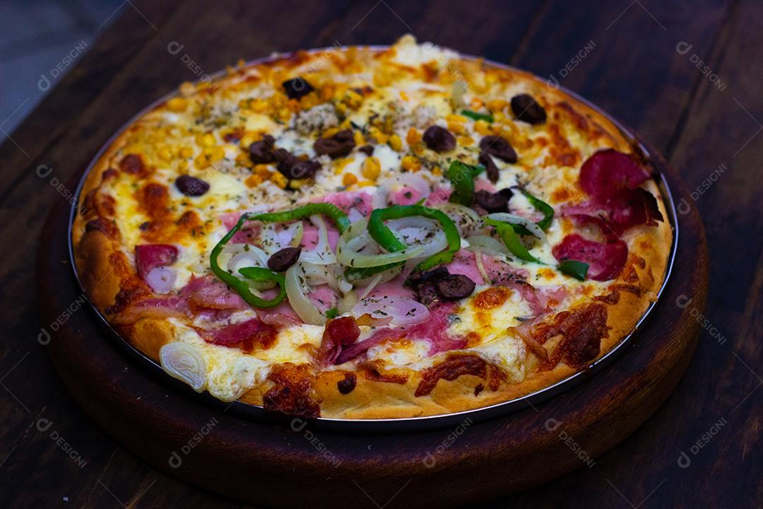 Pizza super deliciosa de queijo com catupiry, calabresa, pimentão verde, cebola branca sobre mesa madeira