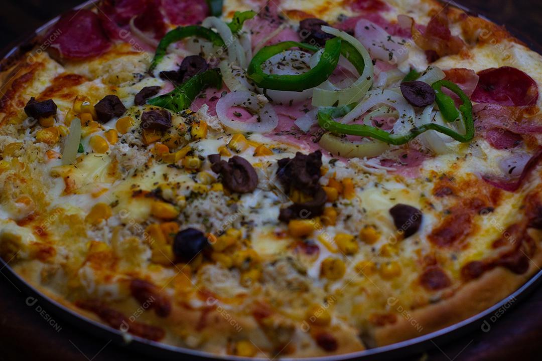 Pizza super deliciosa de queijo com catupiry, calabresa, frango, pimentão verde, cebola branca sobre mesa madeira