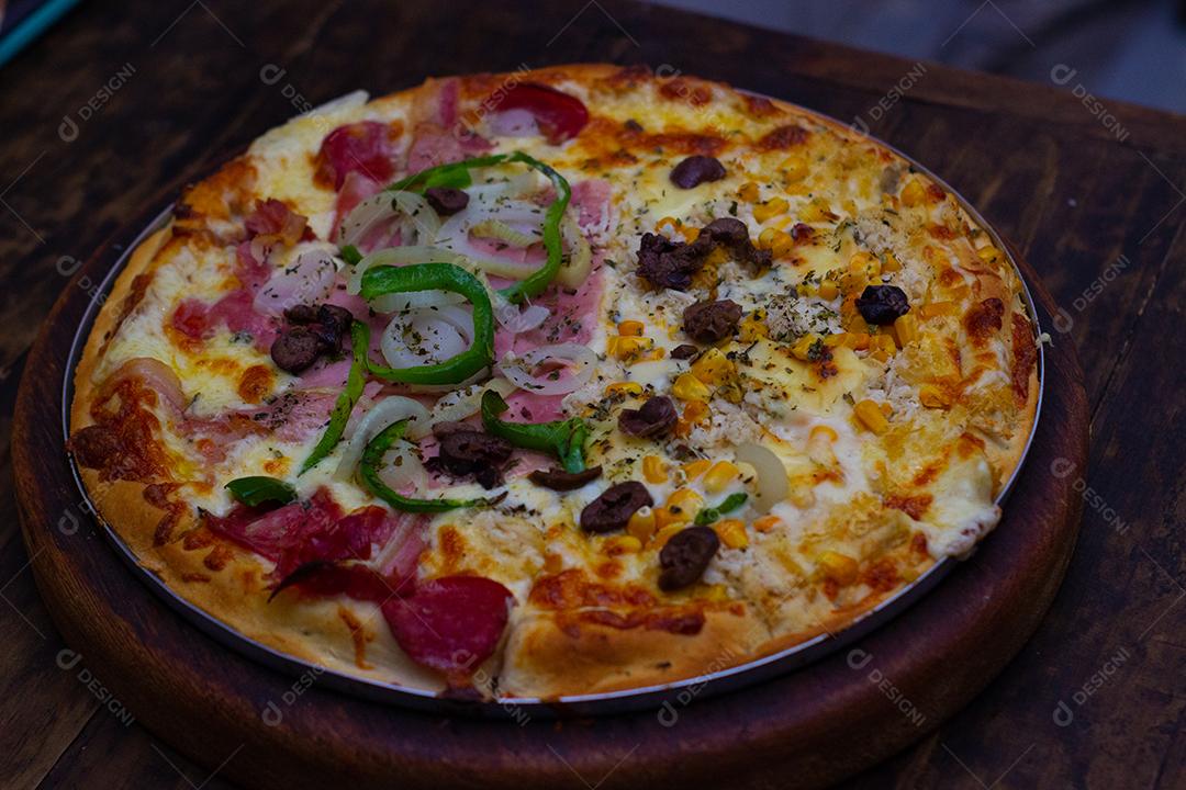 Pizza super deliciosa de queijo com catupiry, calabresa, pimentão verde, cebola branca sobre mesa madeira