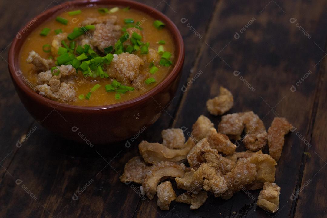 Sopa de bacon com milho em uma tigela sobre mesa madeira.