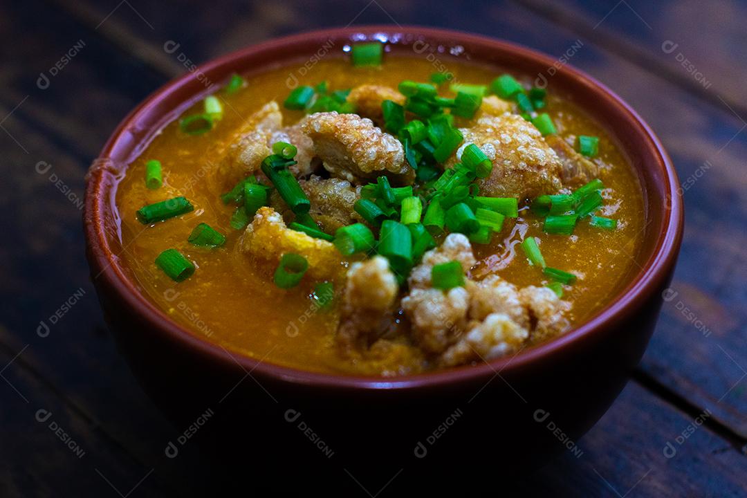 Sopa de bacon com milho em uma tigela sobre mesa madeira.
