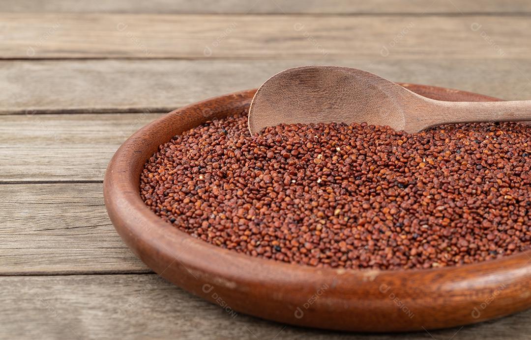 Foco estreito, quinoa vermelha crua em um prato sobre a mesa de madeira.