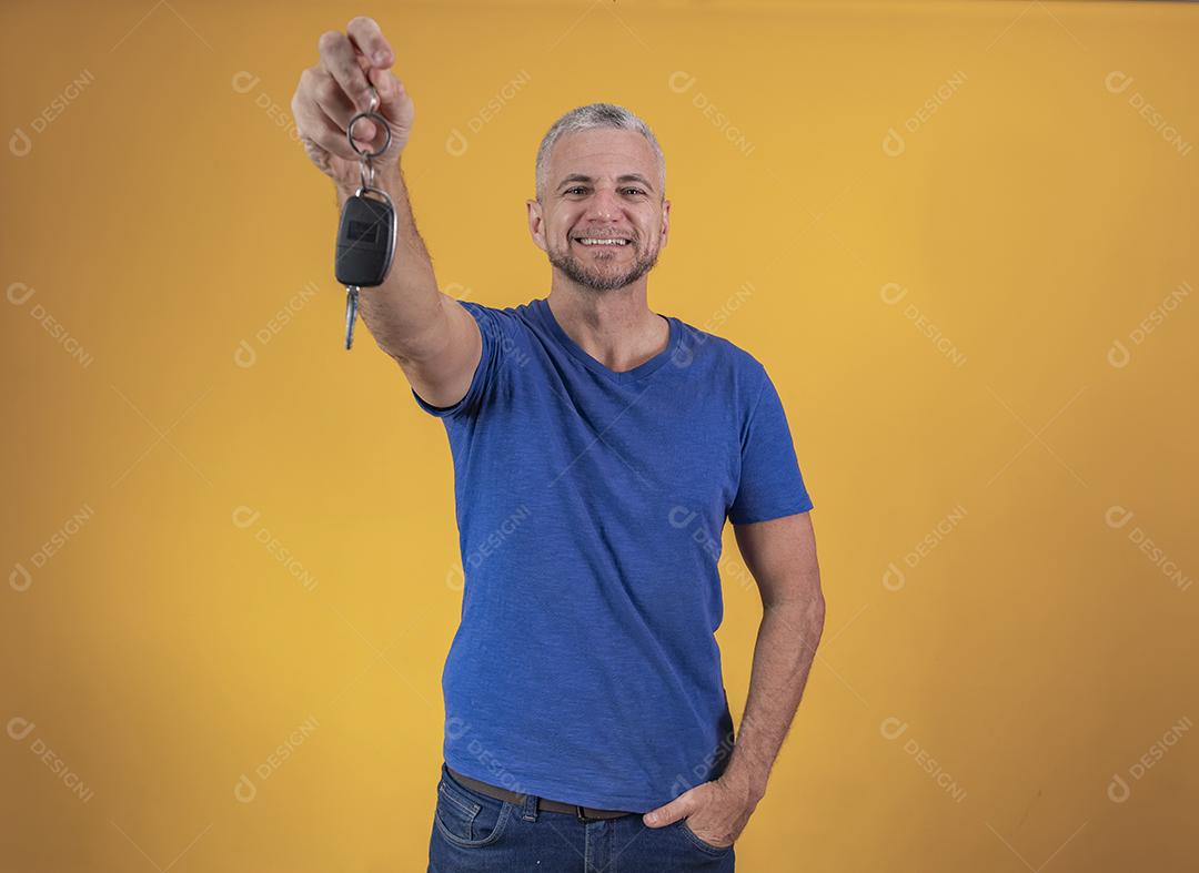 Homem de meia idade feliz sorrindo segurando uma chave de carro