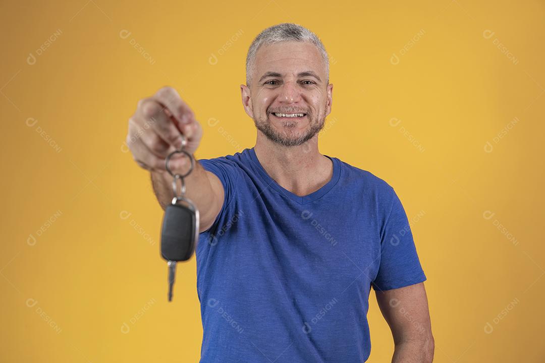 Homem de meia idade feliz sorrindo segurando uma chave de carro