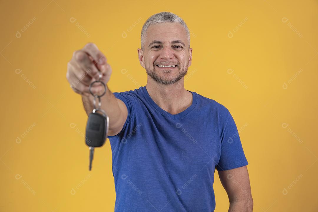 Homem de meia idade feliz sorrindo segurando uma chave de carro