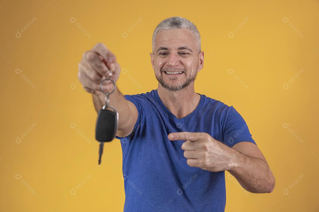 Homem de meia idade feliz sorrindo segurando uma chave de carro
