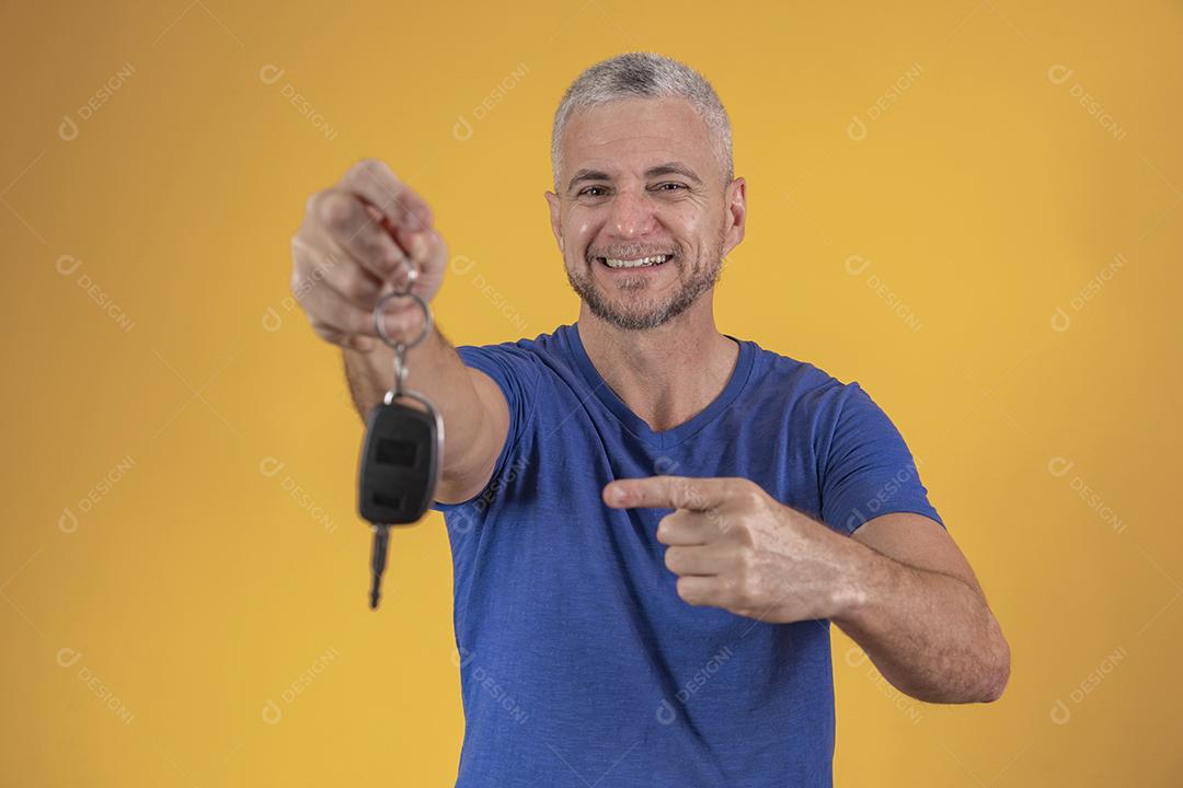 Homem de meia idade feliz sorrindo segurando uma chave de carro