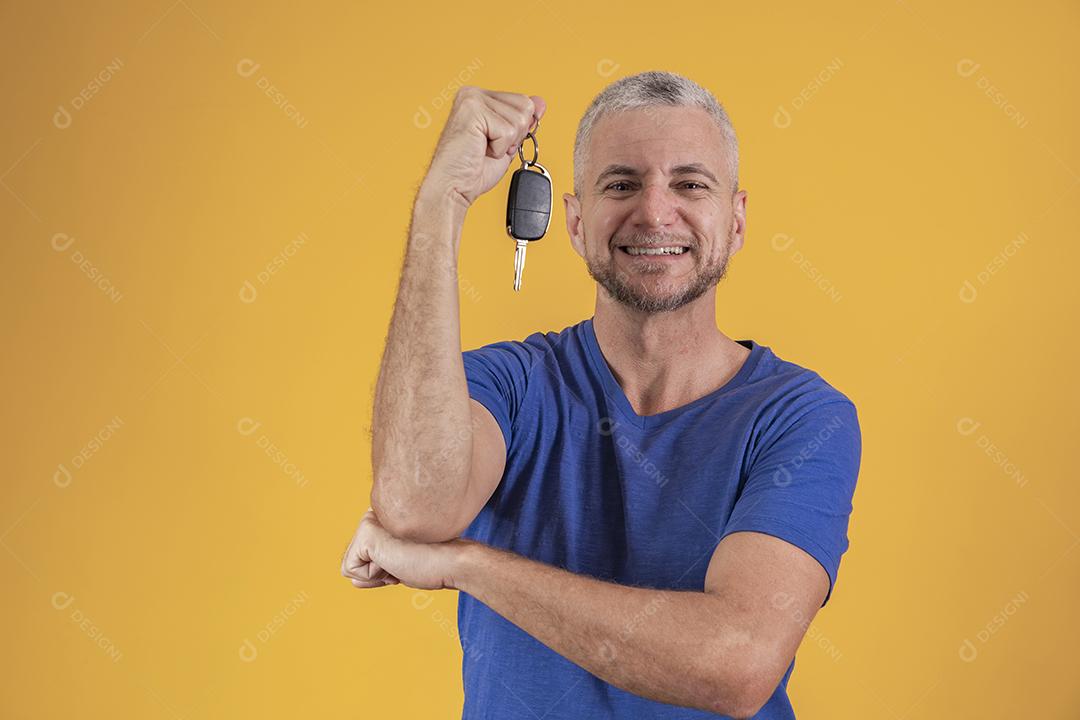 Homem de meia idade feliz sorrindo segurando uma chave de carro