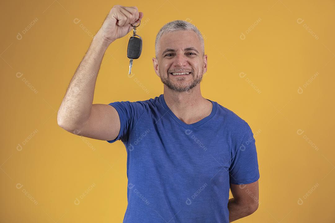 Homem de meia idade feliz sorrindo segurando uma chave de carro