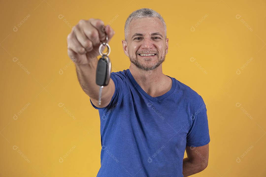 Homem de meia idade feliz sorrindo segurando uma chave de carro