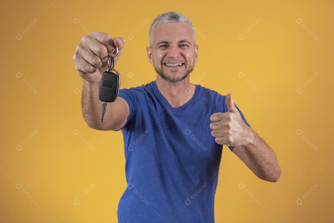 Homem de meia idade feliz sorrindo segurando uma chave de carro