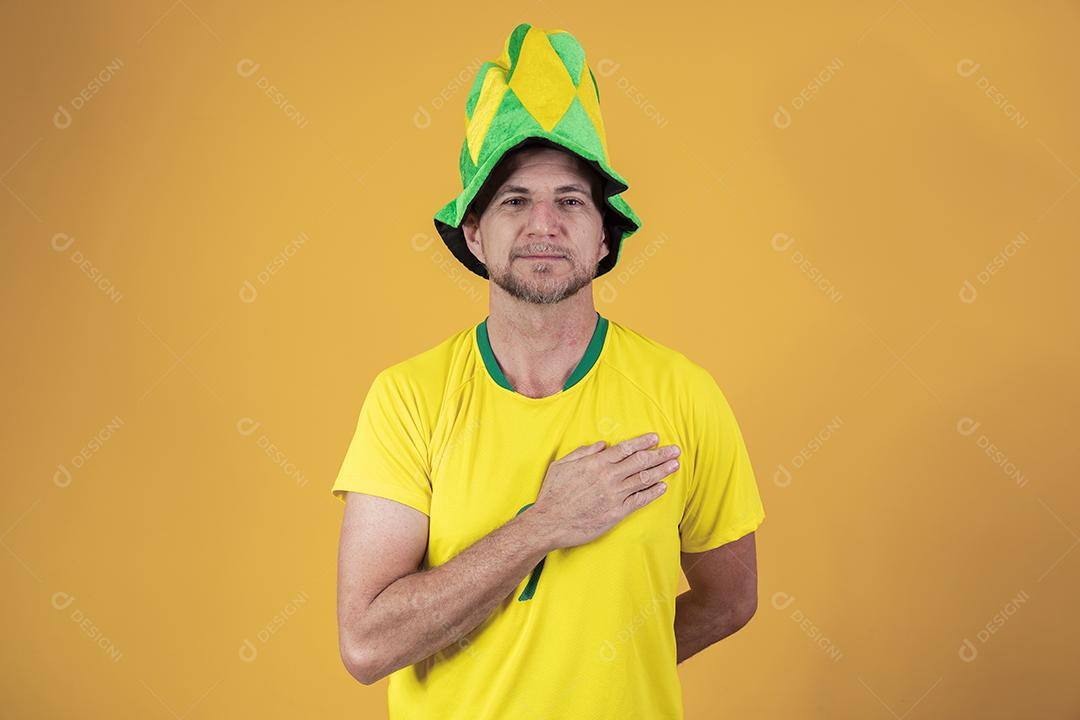 Fã brasileiro com a mão no peito cantando o hino nacional