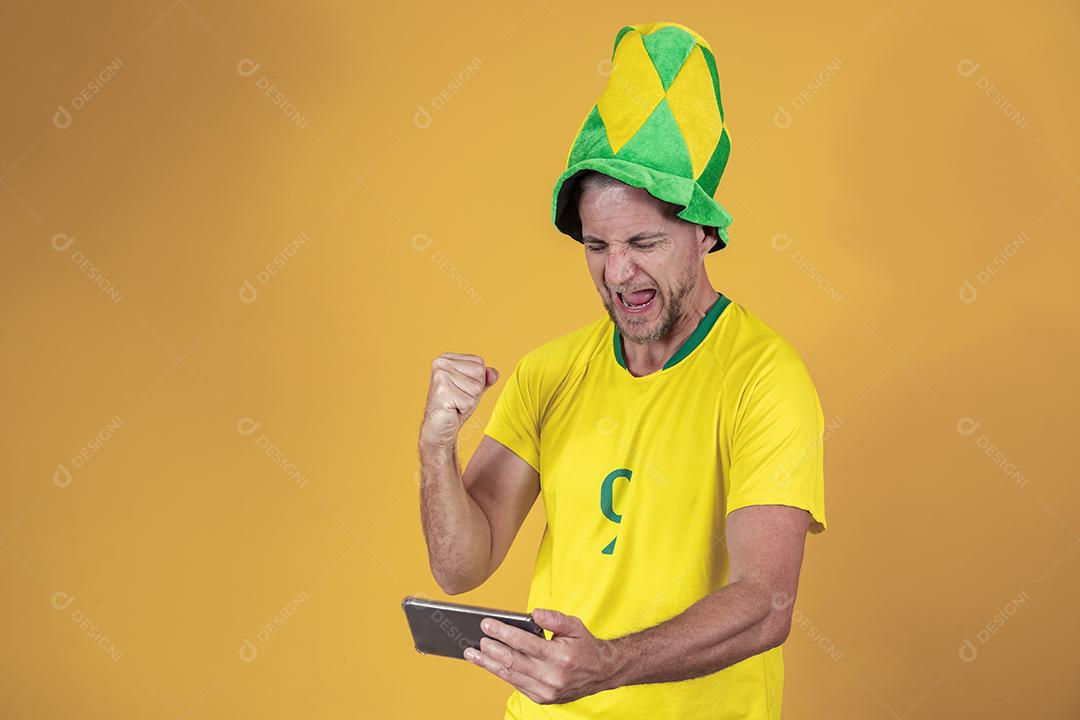 Fã brasileiro de meia idade assistindo jogo pelo celular