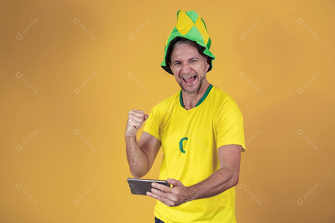 Fã brasileiro de meia idade assistindo jogo pelo celular