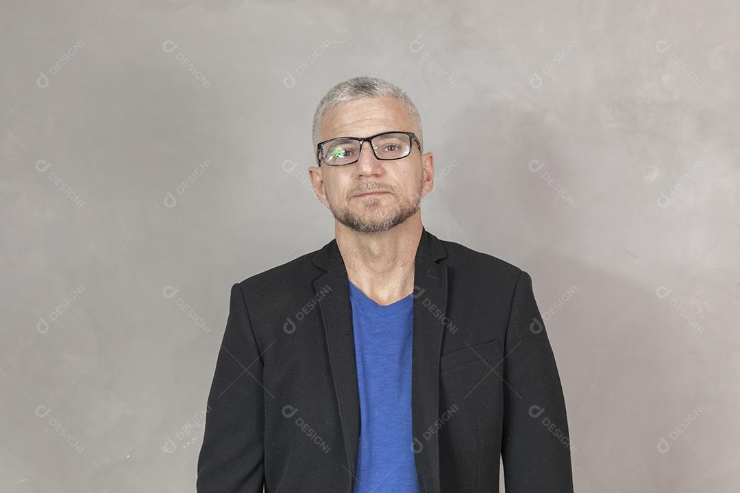 Homem maduro com óculos sorrindo em fundo cinza sorrindo