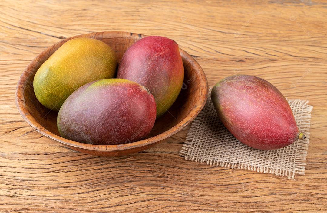 Um grupo de mangas maduras sobre a mesa de madeira.