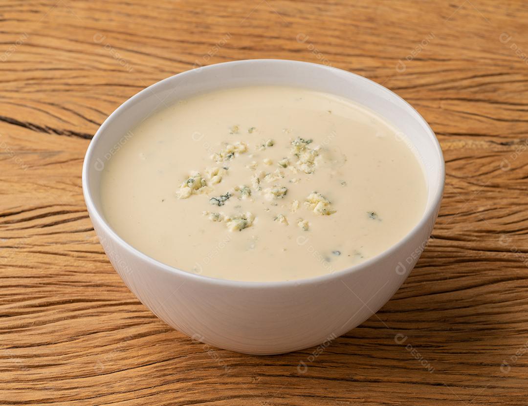 Sopa de queijo em uma tigela sobre a mesa de madeira.