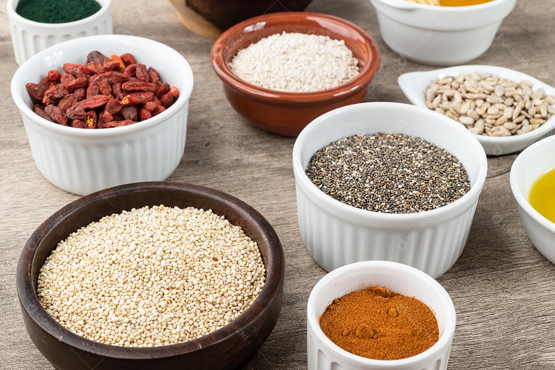 Superalimentos variados sobre fundo de pedra. Chia, quinoa, aveia, linhaça, mel, espirulina e outros.
