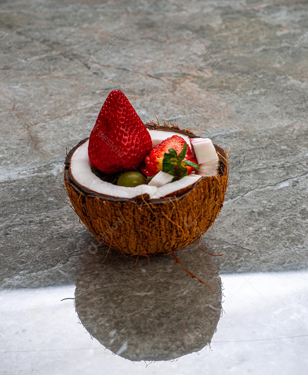 Morangos em um coco cortado em uma mesa de mármore.