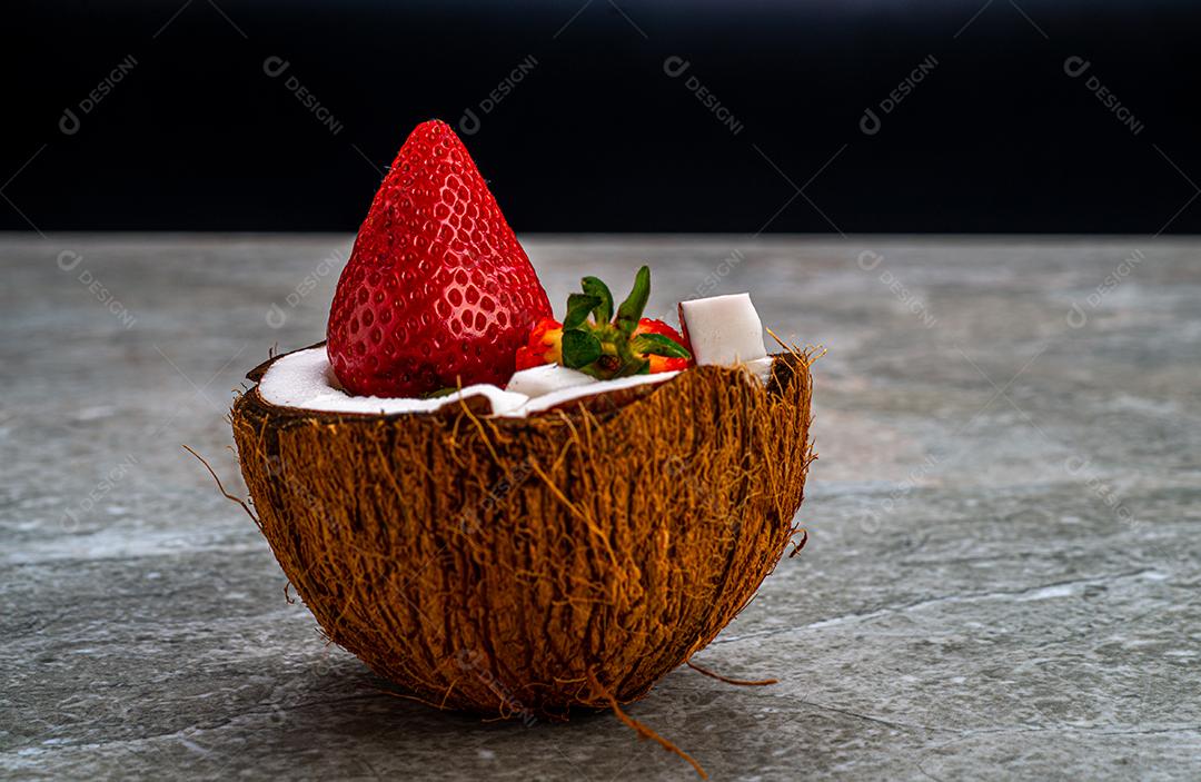 Morangos em um coco cortado em uma mesa de mármore.