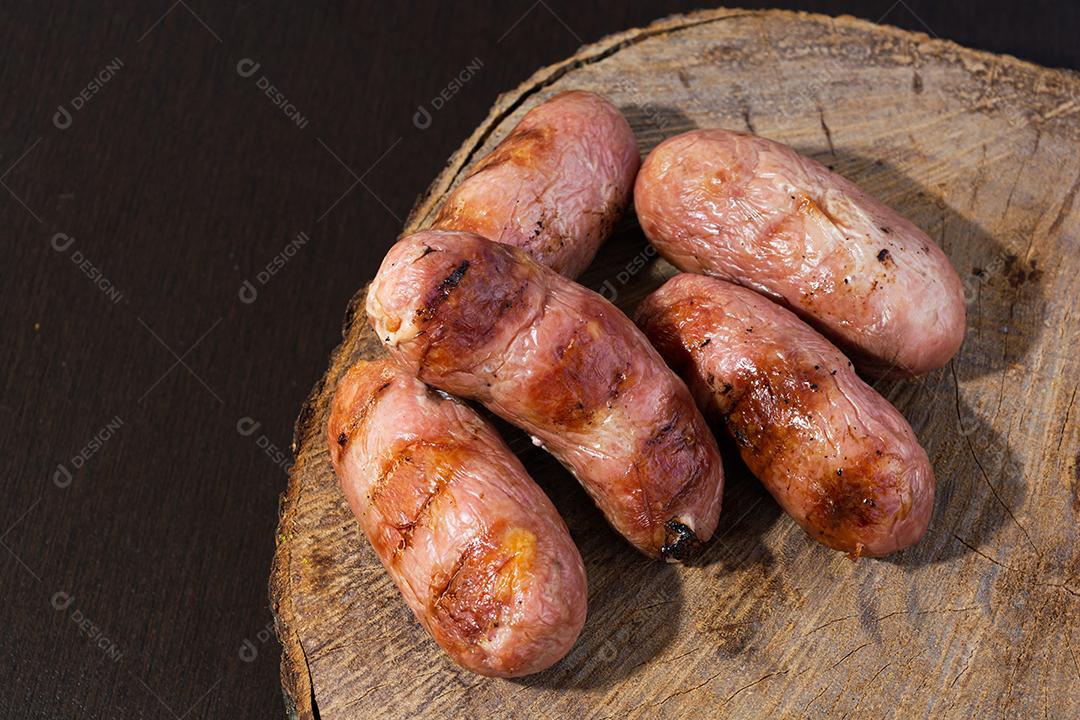 tradicional linguiça de churrasco brasileira com marcas de grelha, mas que ressecaram com o tempo. em cima de uma superfície de madeira