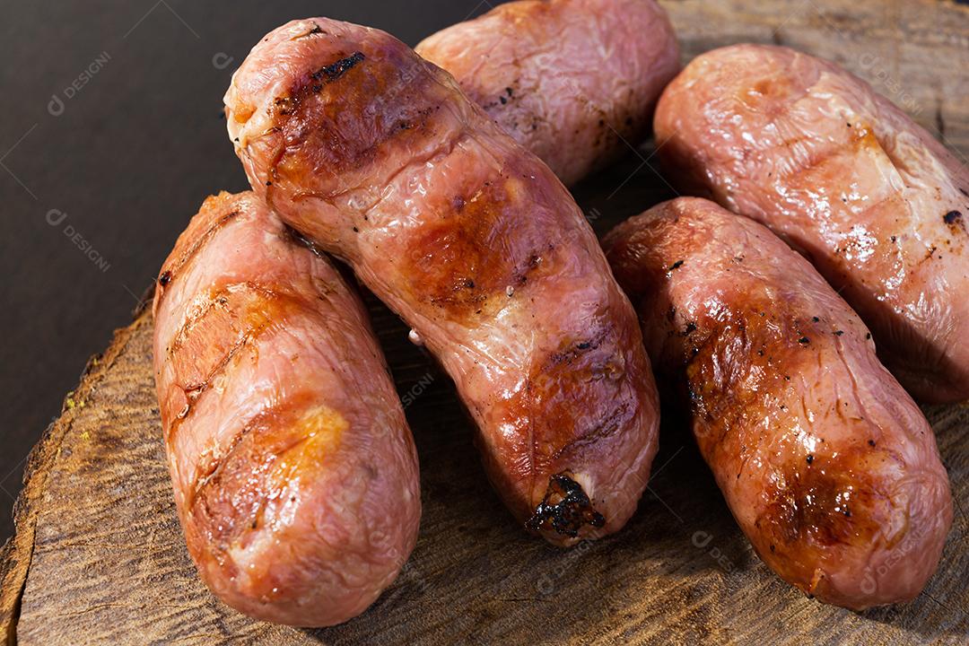 tradicional linguiça de churrasco brasileira com marcas de grelha, mas que ressecaram com o tempo. em cima de uma superfície de madeira