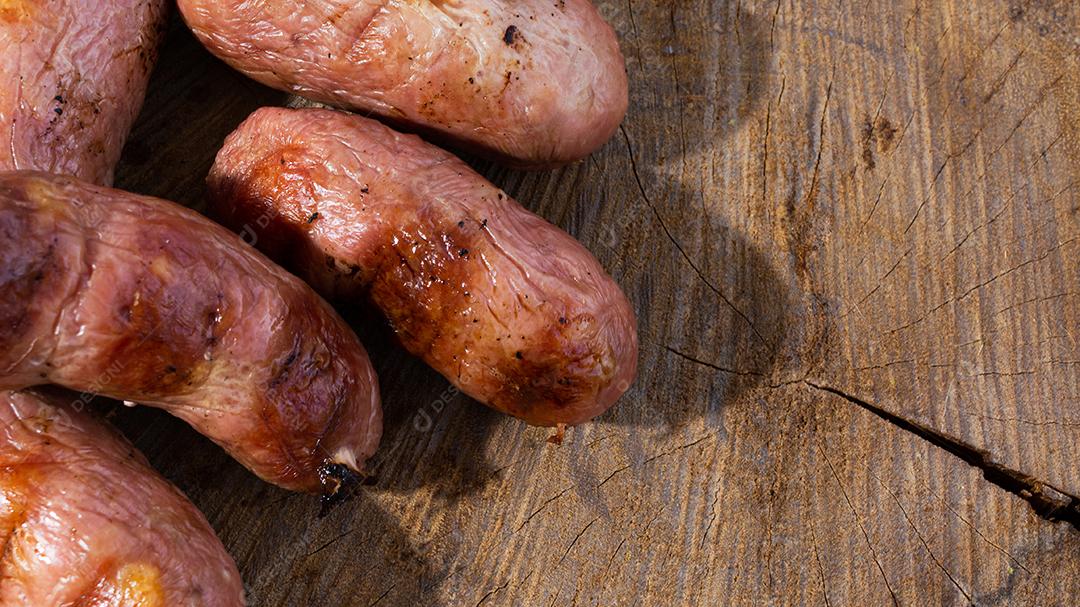 tradicional linguiça de churrasco brasileira com marcas de grelha, mas que ressecaram com o tempo. em cima de uma superfície de madeira