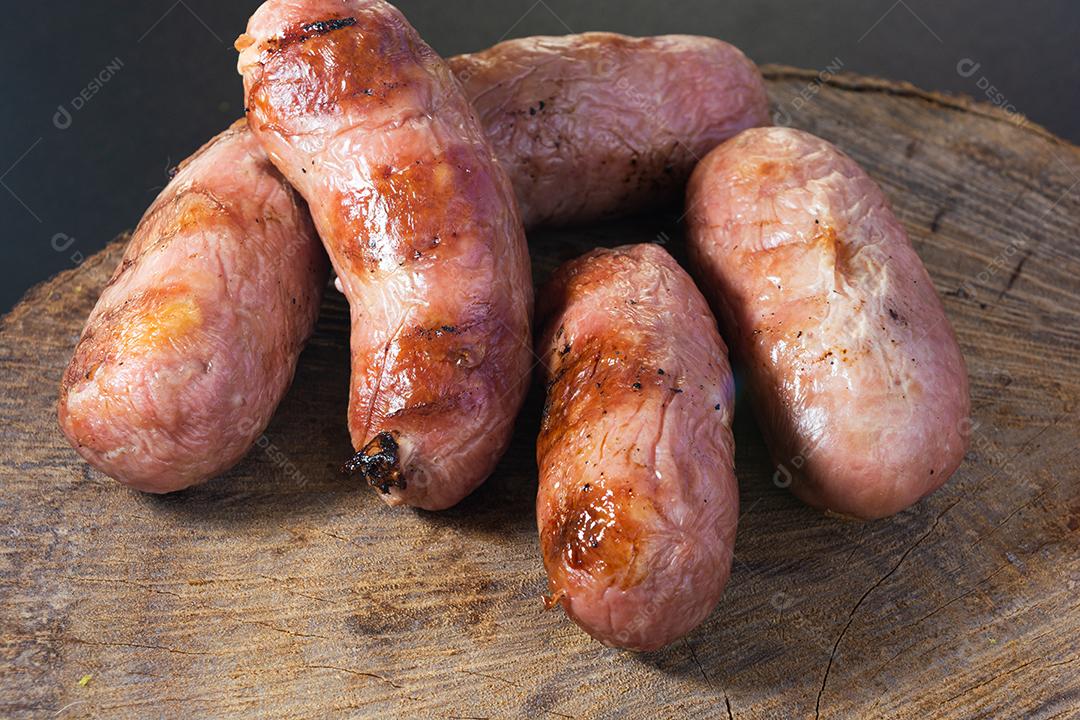 tradicional linguiça de churrasco brasileira com marcas de grelha, mas que ressecaram com o tempo. em cima de uma superfície de madeira