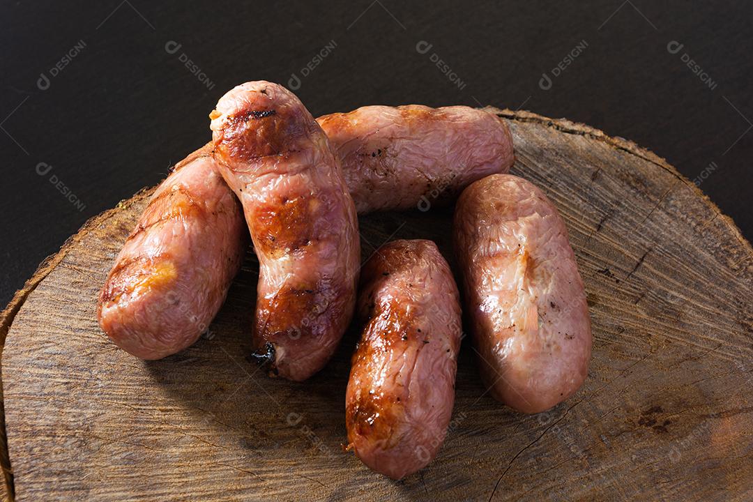 tradicional linguiça de churrasco brasileira com marcas de grelha, mas que ressecaram com o tempo. em cima de uma superfície de madeira