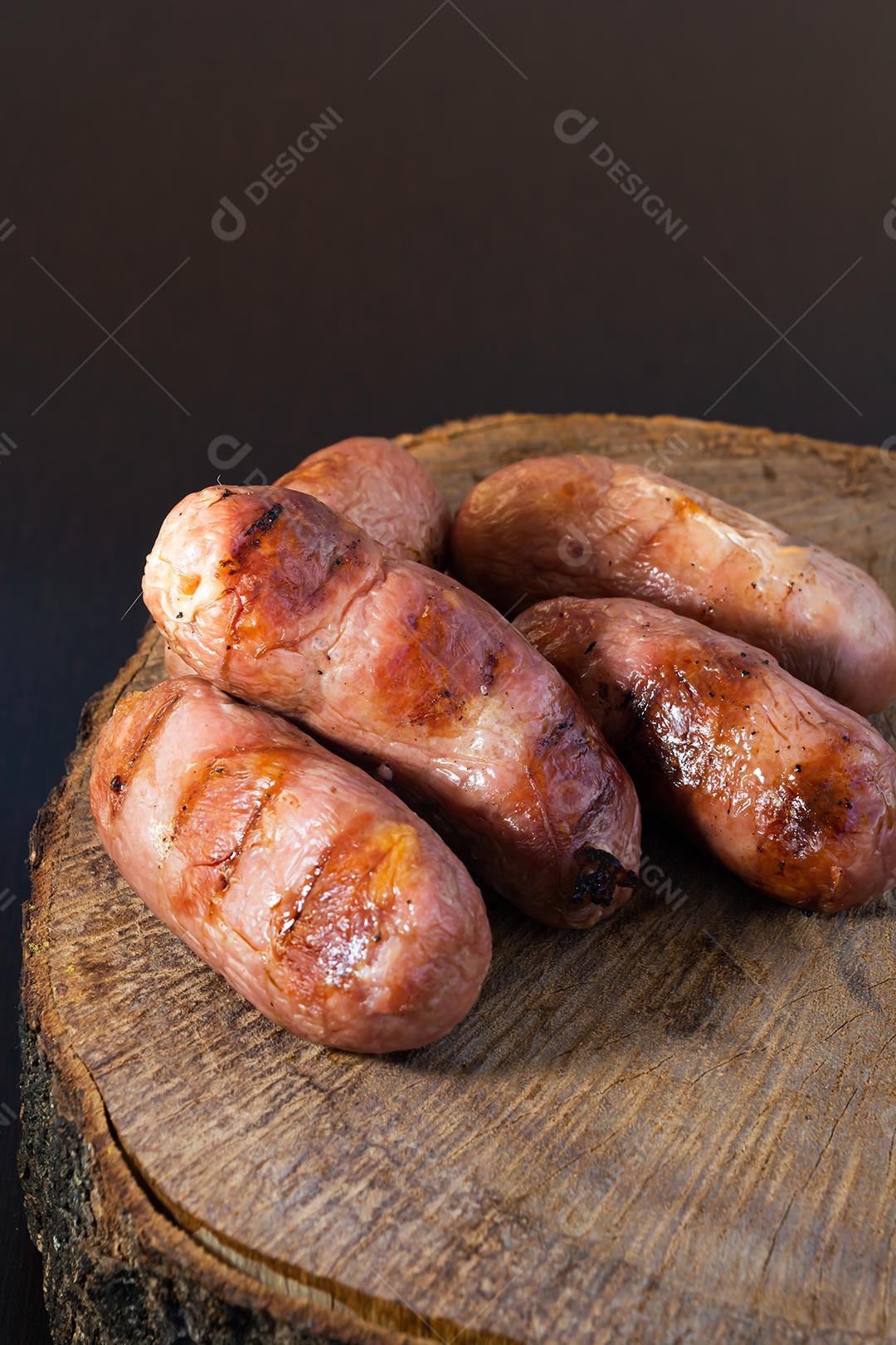 tradicional linguiça de churrasco brasileira com marcas de grelha, mas que ressecaram com o tempo. em cima de uma superfície de madeira