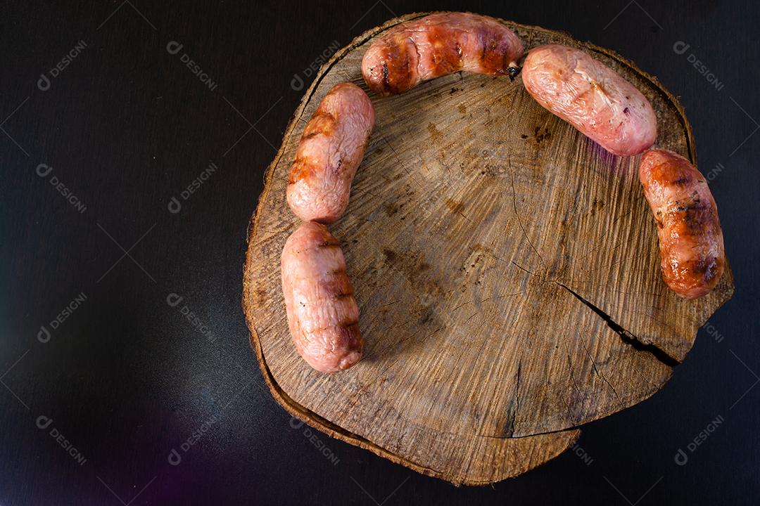 tradicional linguiça de churrasco brasileira com marcas de grelha, mas que ressecaram com o tempo. em cima de uma superfície de madeira