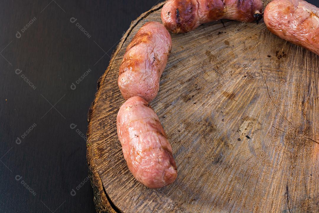 tradicional linguiça de churrasco brasileira com marcas de grelha, mas que ressecaram com o tempo. em cima de uma superfície de madeira