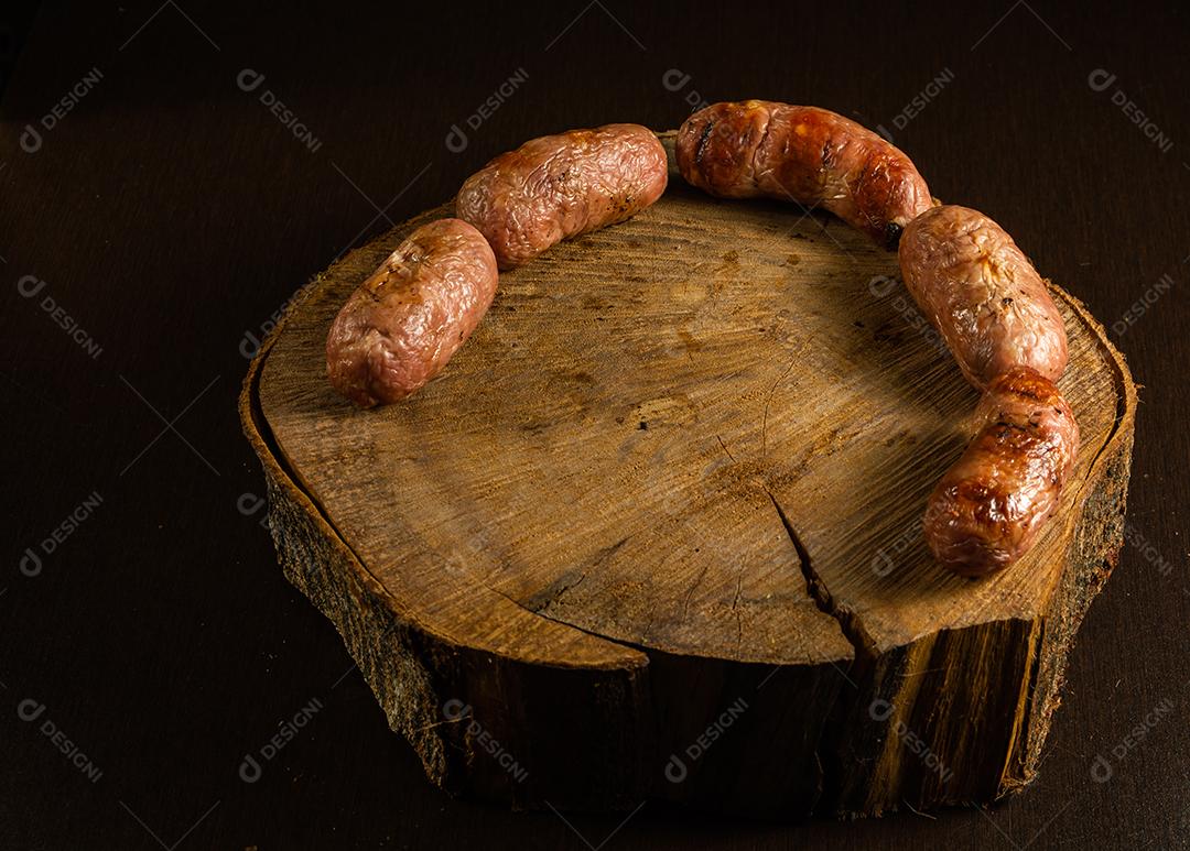 tradicional linguiça de churrasco brasileira com marcas de grelha, mas que ressecaram com o tempo. em cima de uma superfície de madeira