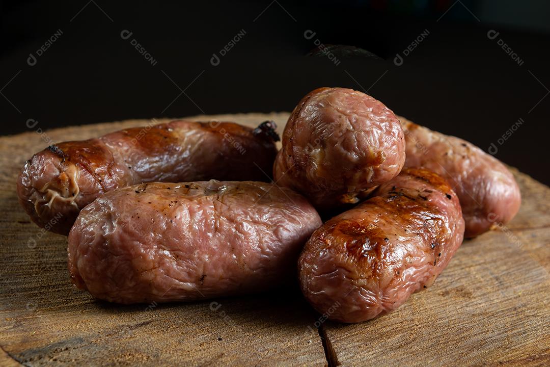 tradicional linguiça de churrasco brasileira com marcas de grelha, mas que ressecaram com o tempo. em cima de uma superfície de madeira