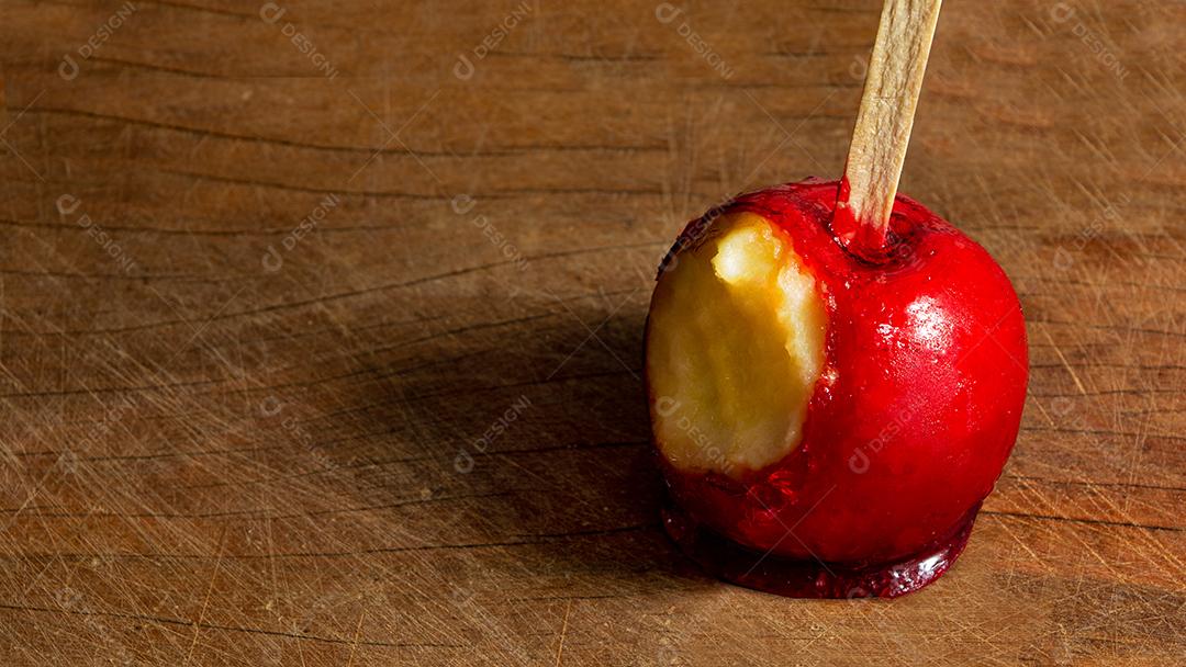 Maçã do amor caramelada, mordida sobre fundo preto