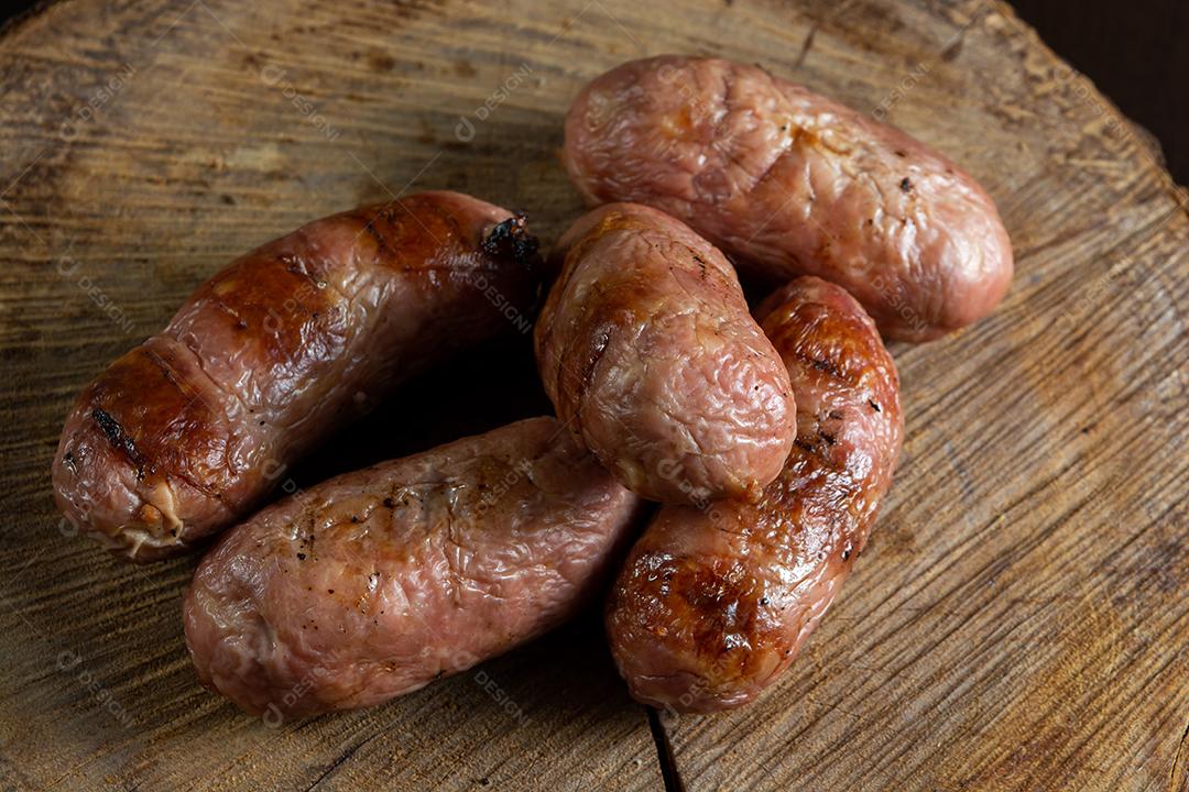 tradicional linguiça de churrasco brasileira com marcas de grelha, mas que ressecaram com o tempo. em cima de uma superfície de madeira