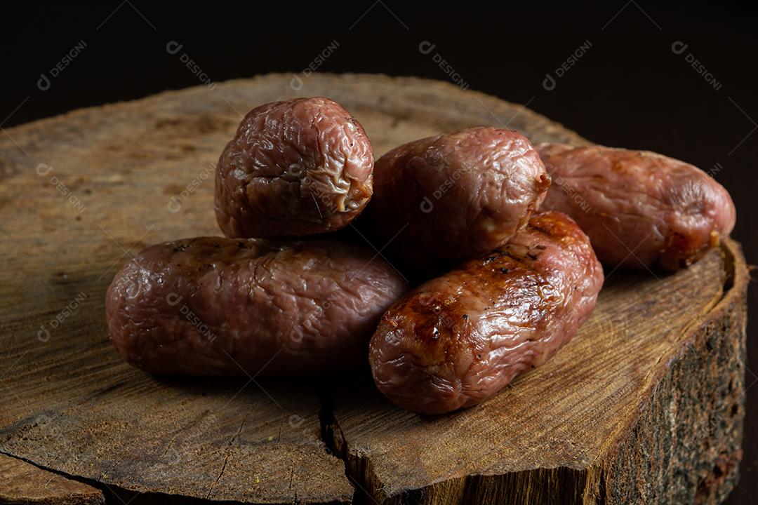 tradicional linguiça de churrasco brasileira com marcas de grelha, mas que ressecaram com o tempo. em cima de uma superfície de madeira
