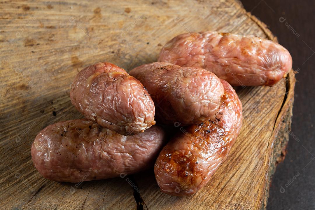 tradicional linguiça de churrasco brasileira com marcas de grelha, mas que ressecaram com o tempo. em cima de uma superfície de madeira