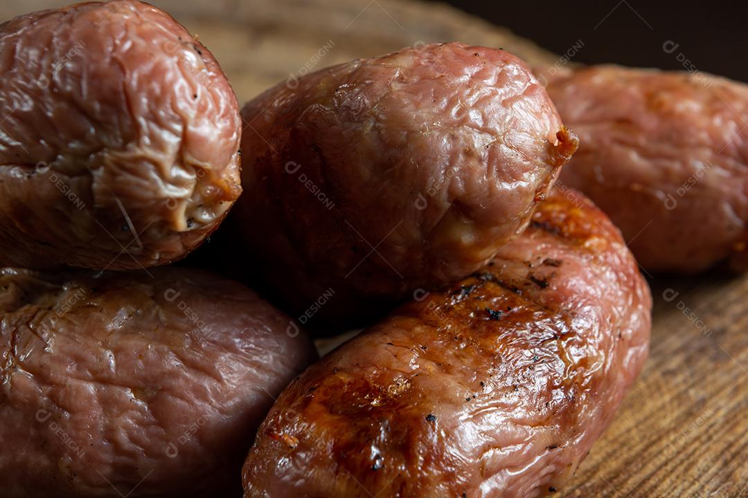 tradicional linguiça de churrasco brasileira com marcas de grelha, mas que ressecaram com o tempo. em cima de uma superfície de madeira