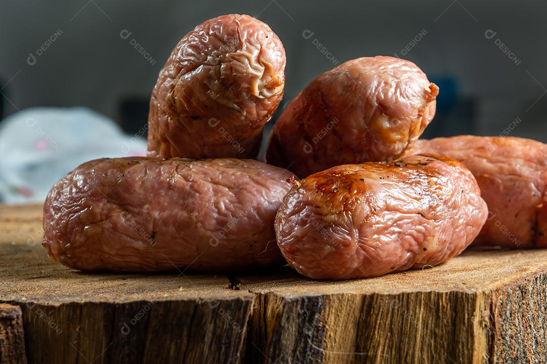 tradicional linguiça de churrasco brasileira com marcas de grelha, mas que ressecaram com o tempo. em cima de uma superfície de madeira