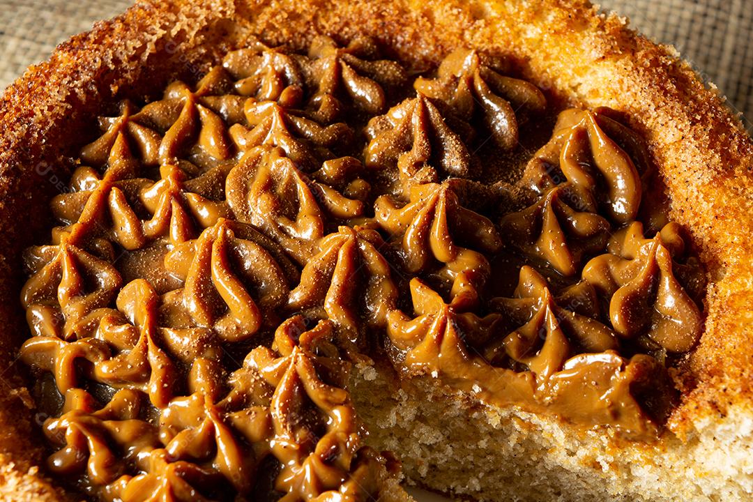 bolo de churros brasileiro típico com doce de leite, em uma mesa com pratos e café, café da manhã confortável ou cena de lanche